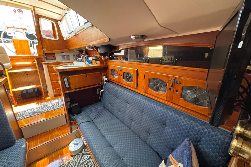 Interior of a 1989 Gulf Pilot House boat with wooden cabinetry and blue seating.