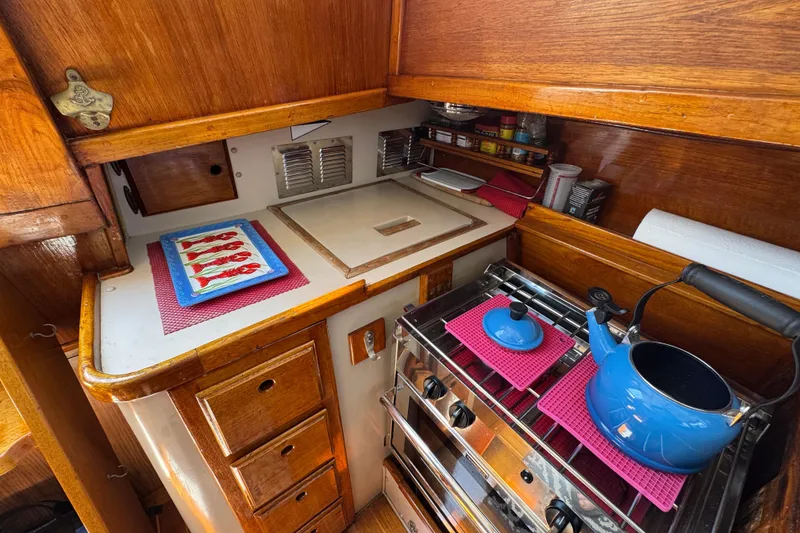 Cozy 1989 Gulf Pilot House kitchen with wooden cabinetry and blue kettle on stove.