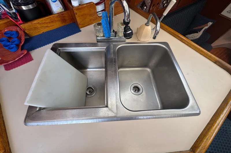 Stainless steel double sink in 1989 Gulf Pilot House kitchen with faucet and cutting board.