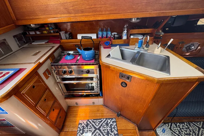 1989 Gulf Pilot House kitchen with stove, sink, and wooden cabinetry.