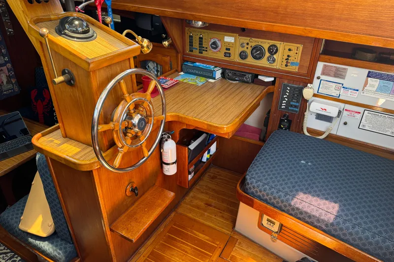 1989 Gulf Pilot House interior with wooden helm, navigation instruments, and seating area.