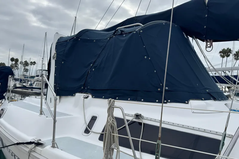 1999 Hunter Passage 420 sailboat with blue canvas cover docked at marina.
