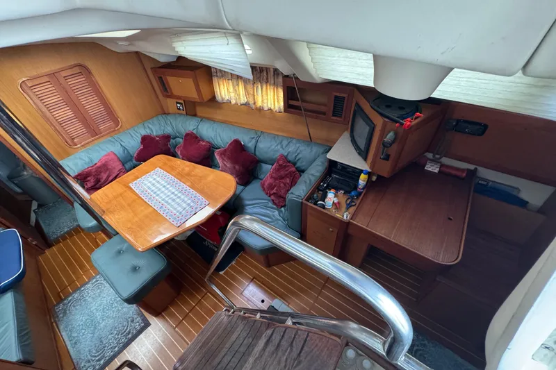Interior of 1999 Hunter Passage 420 yacht with cozy seating and wooden furnishings.
