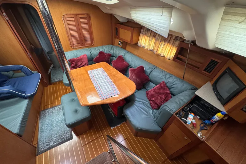 Interior of 1999 Hunter Passage 420 yacht with cozy seating and wooden finishes.