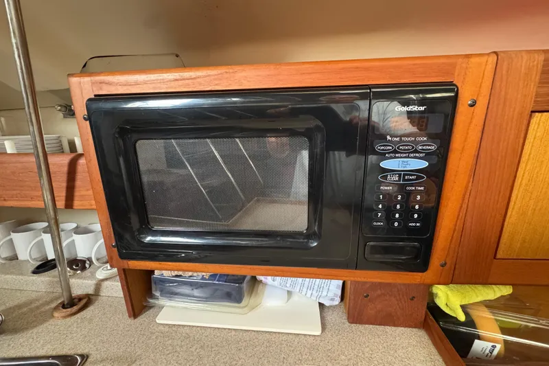 Microwave in 1999 Hunter Passage 420 yacht kitchen, surrounded by wooden cabinetry.