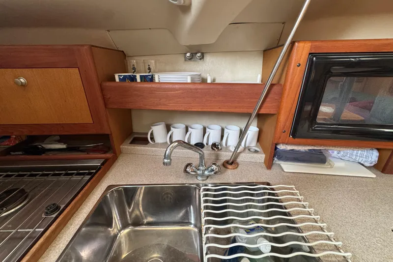 1999 Hunter Passage 420 yacht kitchen with sink, stove, and storage shelves.