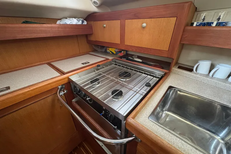 1999 Hunter Passage 420 yacht kitchen with stove, sink, and wooden cabinetry.