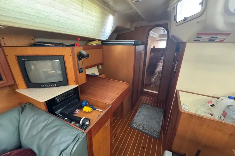Interior of 1999 Hunter Passage 420 sailboat with TV, storage, and cozy cabin space.