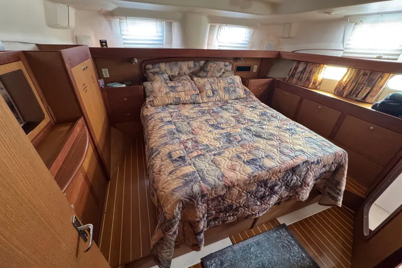 Cozy cabin interior of 1999 Hunter Passage 420 sailboat with bed and wooden furnishings.