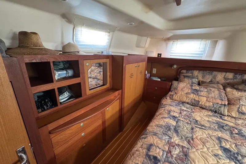 Cozy cabin interior of 1999 Hunter Passage 420 sailboat with wooden storage and bed.