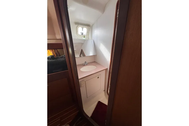 Compact bathroom in 1999 Hunter Passage 420 sailboat with sink and mirror.