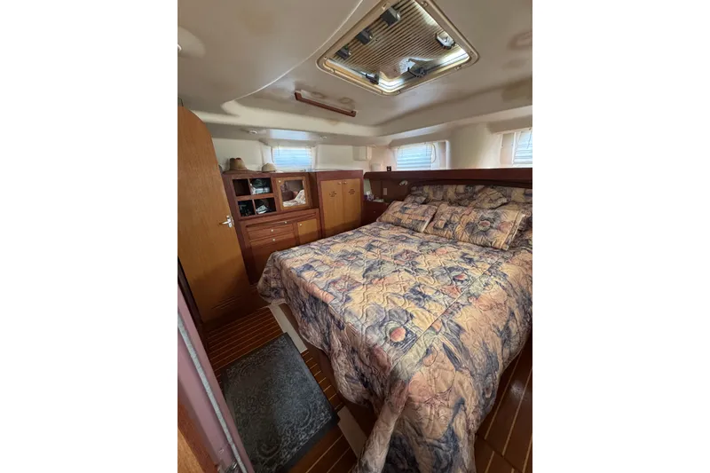 Cozy cabin interior of 1999 Hunter Passage 420 sailboat with patterned bedding and wooden cabinetry.