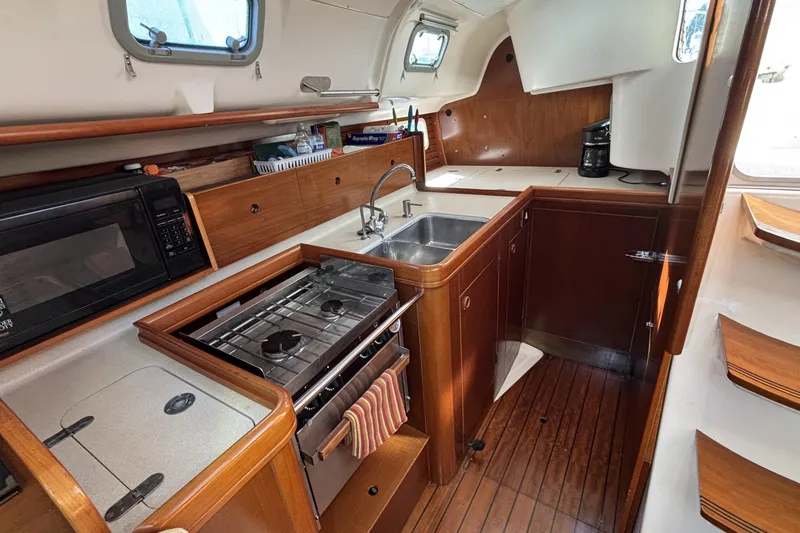 Interior of 1997 Beneteau Oceanis 400 yacht kitchen with stove, sink, and microwave.