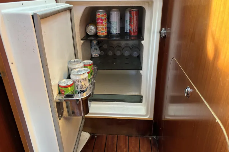 Mini fridge on 1997 Beneteau Oceanis 400 yacht, stocked with drinks and water bottles.