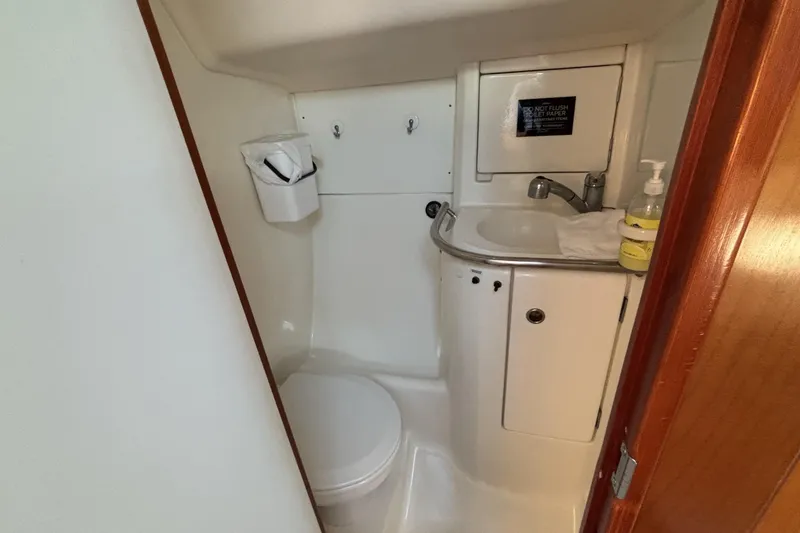 Bathroom interior of 1997 Beneteau Oceanis 400 yacht, featuring compact sink and toilet.