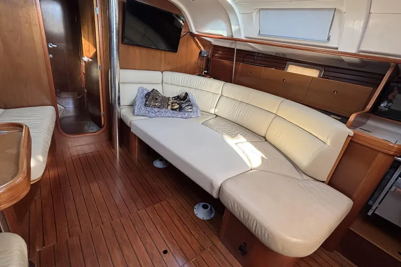 Interior of 1997 Beneteau Oceanis 400 yacht with cream leather seating and wooden flooring.