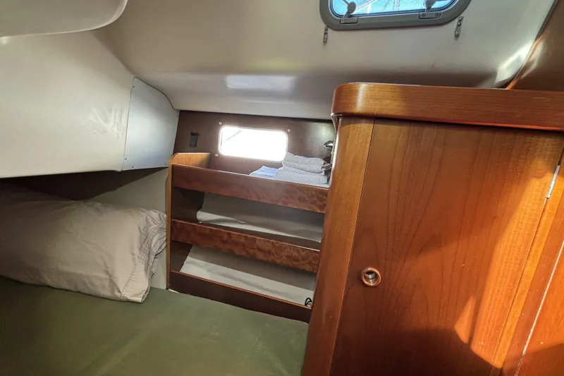 Cozy cabin interior of 1997 Beneteau Oceanis 400 sailboat with wooden shelves and bedding.