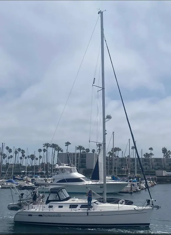 2006 Hunter 41 Deck Salon sailboat in a marina with palm trees and cloudy sky.