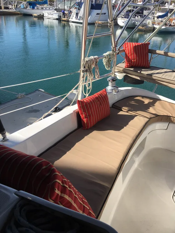 2006 Hunter 41 Deck Salon yacht with cushioned seating and red pillows in a marina.