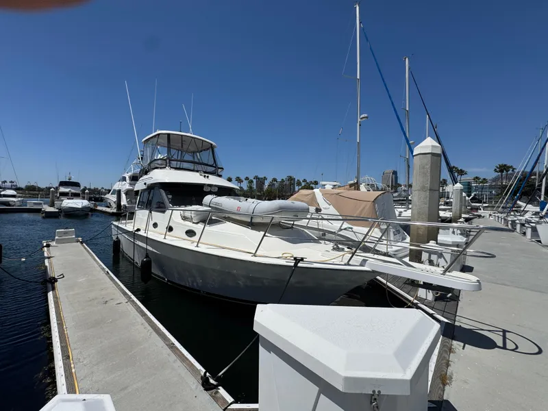 2003 Mediterranean 38 Convertible yacht docked at marina under clear blue sky.