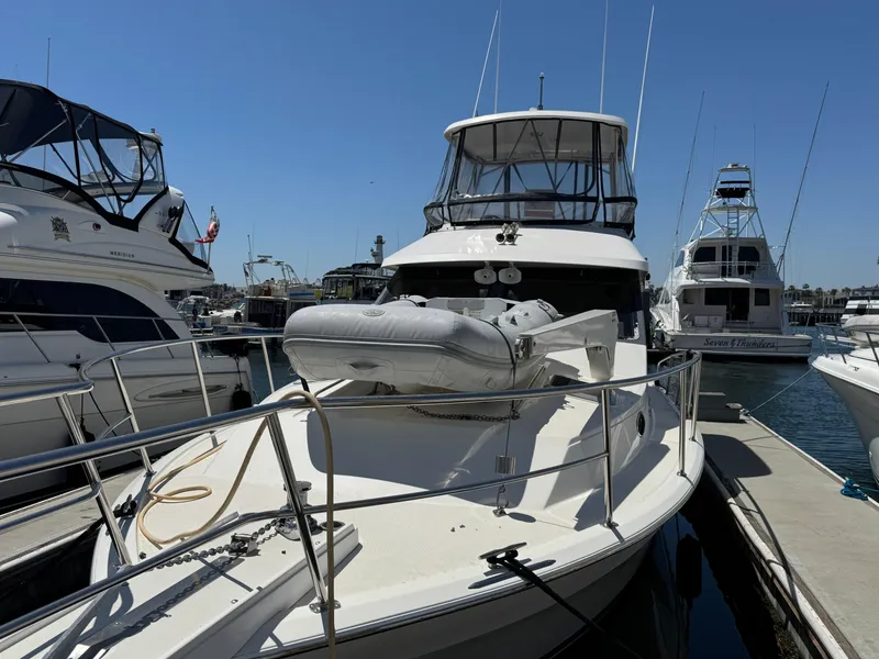 2003 Mediterranean 38 Convertible yacht docked at marina with inflatable boat on deck.