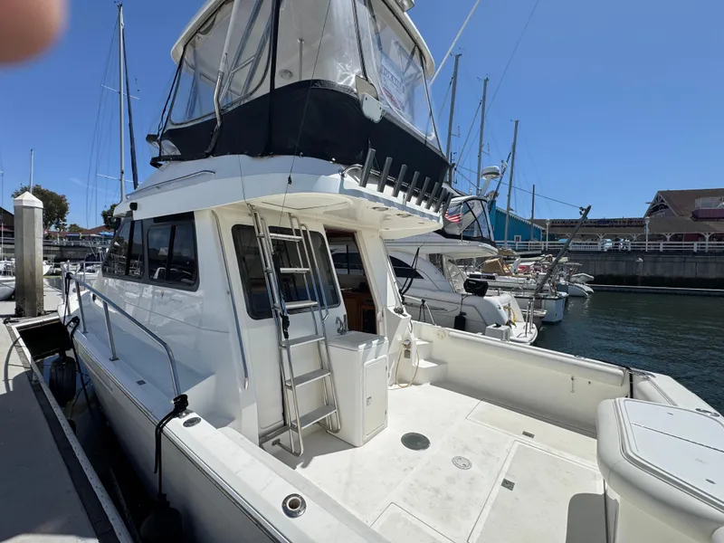 2003 Mediterranean 38 Convertible yacht docked at marina, featuring spacious deck and flybridge.