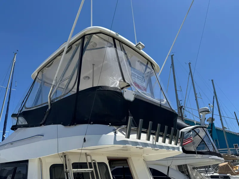 2003 Mediterranean 38 Convertible yacht with enclosed flybridge, docked under clear blue sky.