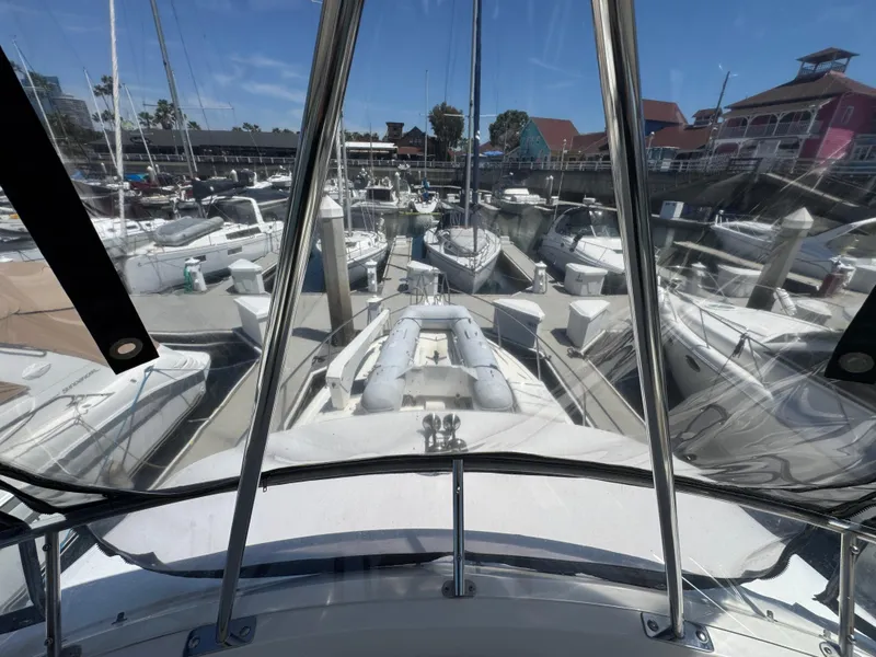 View from 2003 Mediterranean 38 Convertible yacht in marina, surrounded by boats and clear skies.