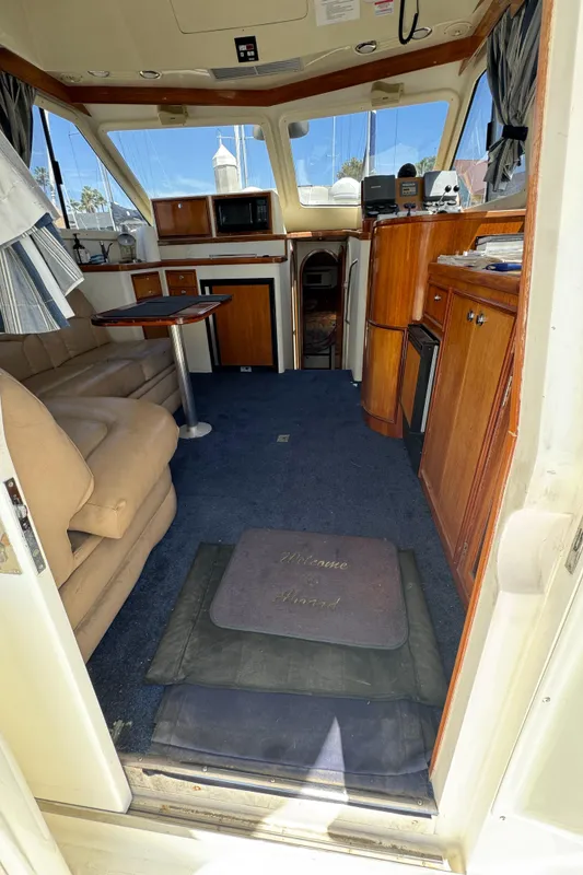 Interior of 2003 Mediterranean 38 Convertible yacht with cozy seating and wooden cabinetry.