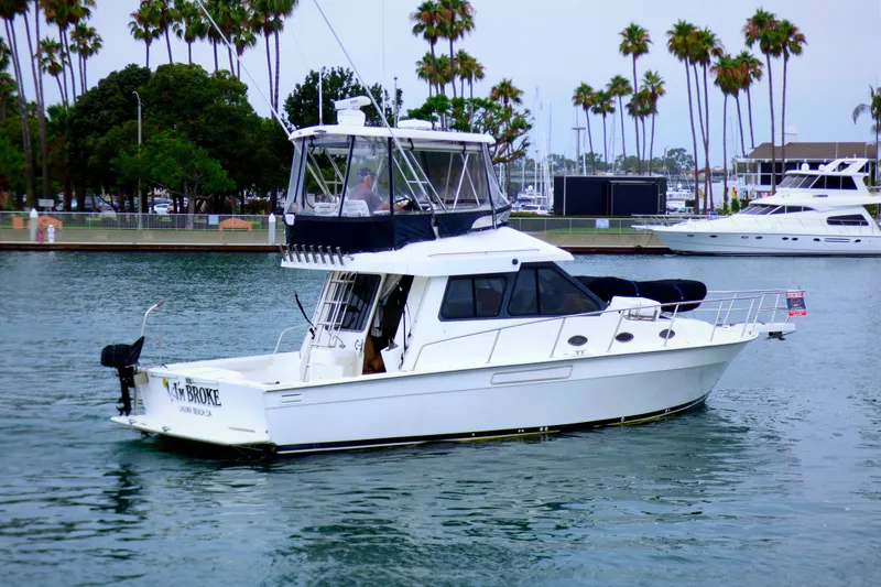 2003 Mediterranean 38 Convertible yacht cruising in a marina with palm trees in the background.