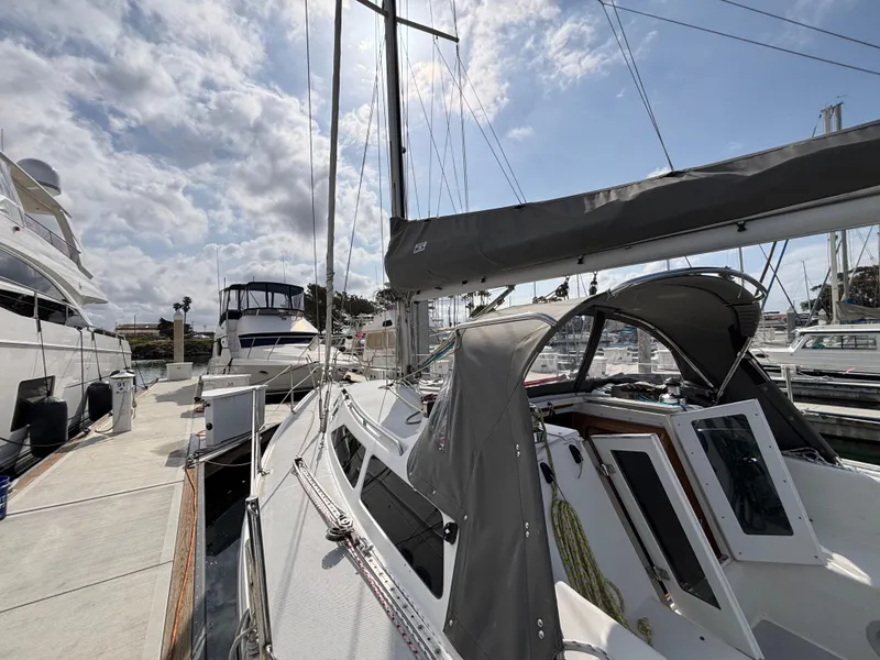 2005 Catalina 320 sailboat docked at marina under partly cloudy sky.