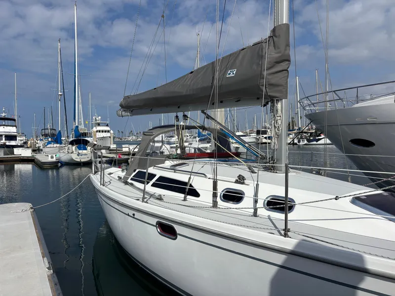 2005 Catalina 320 sailboat docked in marina, surrounded by other boats under a blue sky.