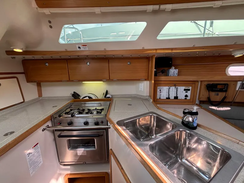 2005 Catalina 320 yacht kitchen with stove, dual sinks, and wooden cabinetry.