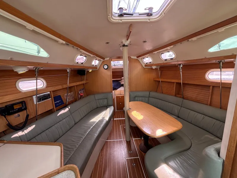 2005 Catalina 320 yacht interior with wood paneling, cushioned seating, and dining table.