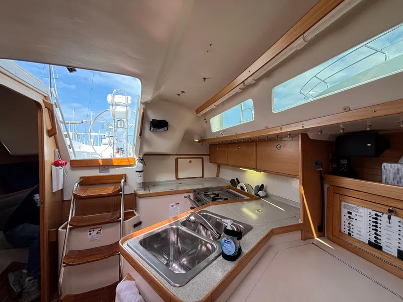 Interior of a 2005 Catalina 320 sailboat, featuring a compact kitchen with wooden cabinetry.