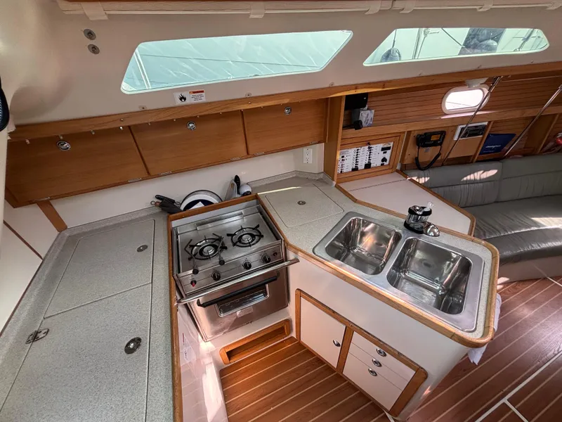 2005 Catalina 320 yacht interior kitchen with stove, double sink, and wooden cabinetry.