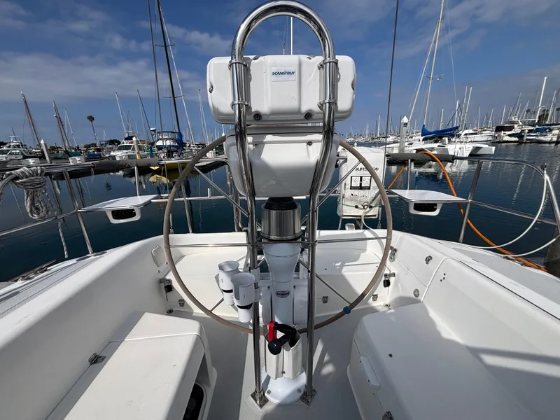 Cockpit view of 2005 Catalina 320 sailboat docked in marina under blue sky.