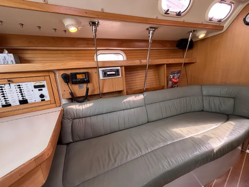 Interior of 2005 Catalina 320 sailboat with beige seating and wooden cabinetry.
