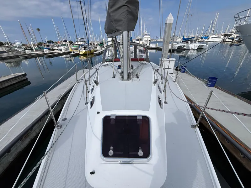 2005 Catalina 320 sailboat docked at marina, surrounded by other boats under a clear sky.