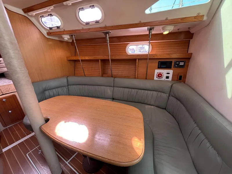 Interior of 2005 Catalina 320 sailboat with cozy seating and wooden table.