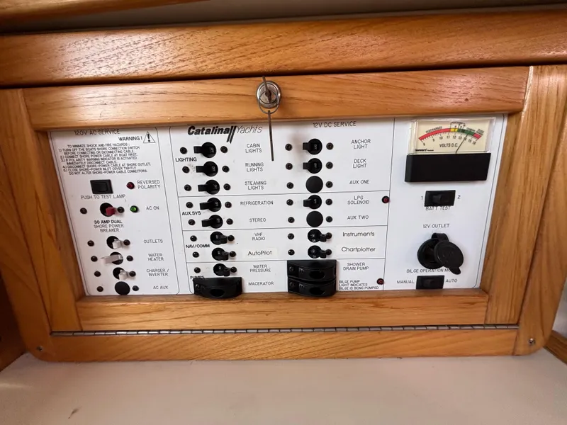 Electrical control panel of a 2005 Catalina 320 sailboat with wooden frame.
