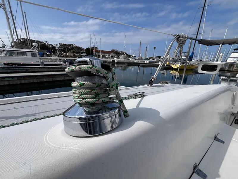 Catalina 320 sailboat winch with rope, docked in marina, under blue sky.