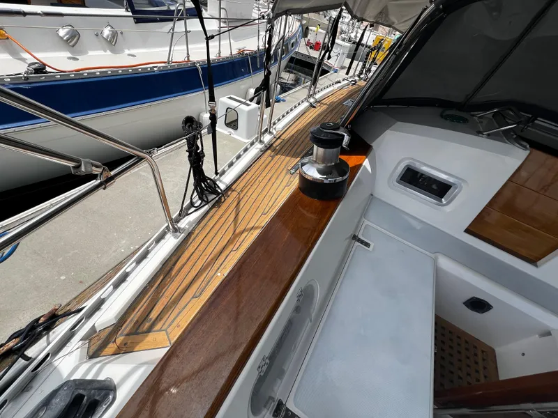 1987 Norseman 400 sailboat deck with wooden finish and winch, docked beside other boats.