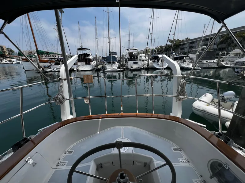 Cockpit view from 1987 Norseman 400 sailboat in marina, surrounded by yachts and calm water.