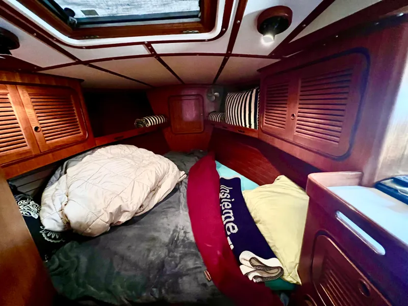 Cozy cabin interior of 1987 Norseman 400 sailboat with bedding and wooden storage.
