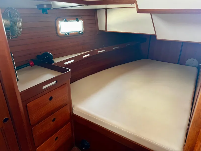 Cozy cabin interior of 1987 Norseman 400 sailboat with wooden furnishings and bed.