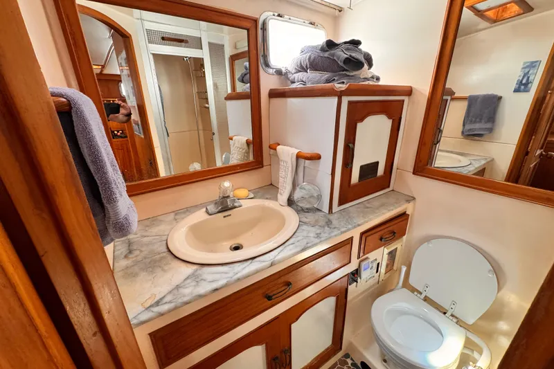 1983 Sea Ranger 45 Sun Deck bathroom with marble countertop, sink, and wooden cabinetry.