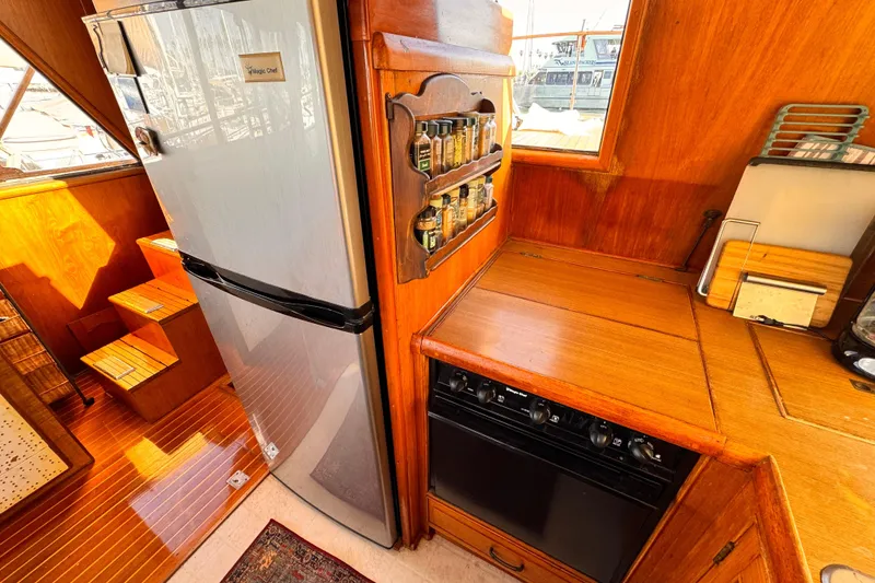 1983 Sea Ranger 45 Sun Deck kitchen with fridge, spice rack, and wooden cabinetry.