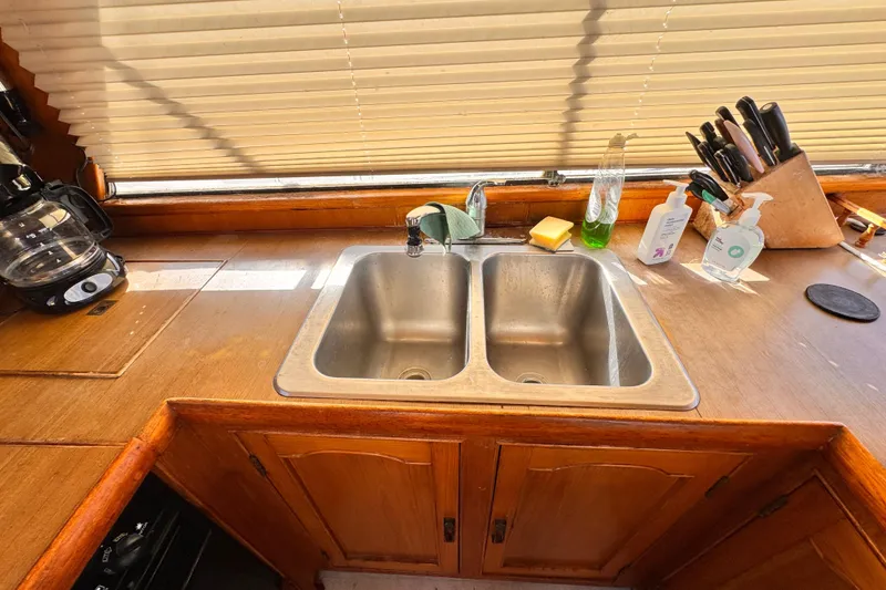 1983 Sea Ranger 45 Sun Deck kitchen with double sink, wooden cabinets, and countertop essentials.