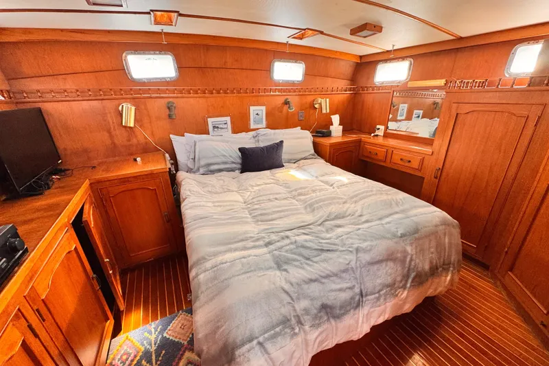 Cozy bedroom in 1983 Sea Ranger 45 Sun Deck yacht with wooden interior and comfortable bedding.